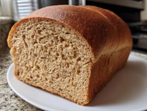 A freshly baked loaf of whole wheat bread, sliced to show its soft, even crumb structure.