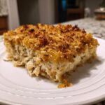 A close-up serving of creamy chicken wild rice casserole topped with a golden brown, crunchy breadcrumb crust.