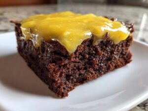 Close-up of a rich, dark chocolate brownie square topped with a thick layer of bright yellow lemon frosting, perfect for lemon brownies.