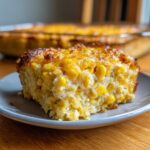 A close-up slice of moist cream cheese corn casserole with whole corn kernels and a browned top.