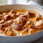 Close-up of seared, bite-sized cajun chicken pieces simmering in a rich, creamy orange sauce.