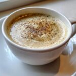 Close-up of a creamy beverage or soup topped with spices, perhaps hinting at the garnish for the roasted cauliflower soup.