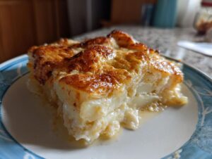 A close-up serving of rich potatoes au gratin with a bubbly, browned cheese crust.