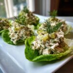 Several servings of dill pickle chicken salad presented in crisp lettuce cups, garnished with dill.