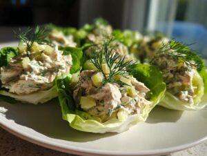 Close-up of dill pickle chicken salad served in crisp lettuce cups, garnished with fresh dill.