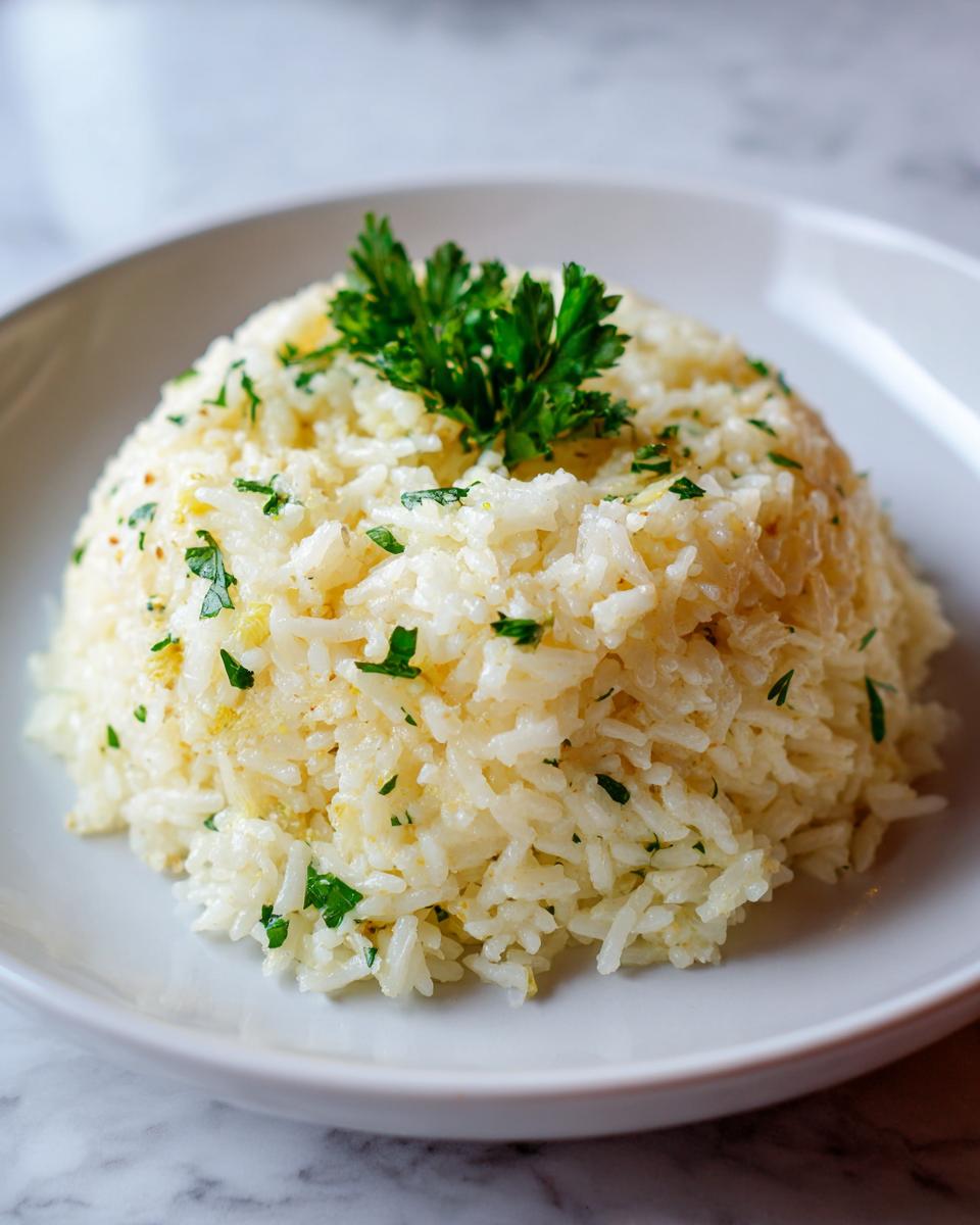 A perfectly molded serving of fluffy garlic butter rice topped with fresh parsley.