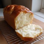 A freshly baked loaf of Japanese milk bread sliced open, showing its incredibly soft and fluffy white interior.