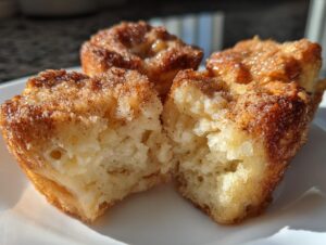A close-up view showing the soft interior of one of the french toast muffins, coated in cinnamon sugar.