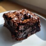 Close-up of a rich, dark, fudgy square of sweet potato brownies with a crackly top.