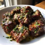 Close-up of juicy garlic butter steak bites topped with minced garlic and fresh parsley.