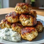 A stack of golden brown, juicy greek chicken meatballs served with a dollop of creamy tzatziki sauce.
