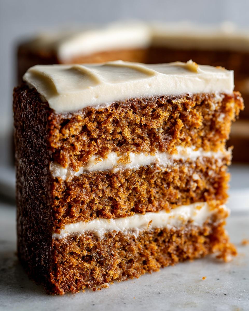 Close-up of a thick slice of three-layer applesauce cake with rich brown crumb and white frosting.