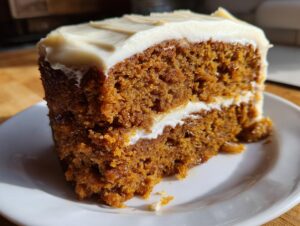Close-up of a moist slice of applesauce cake layered with white cream cheese frosting.