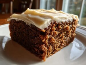 Close-up of a moist, dark slice of gingerbread cake topped with thick, creamy frosting.