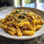A close-up of creamy, cheesy beef pasta made with fusilli noodles, garnished with fresh parsley.