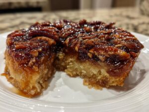 A close-up view of a slice of pecan upside down cake showing the sticky, caramelized pecan topping and moist cake base.
