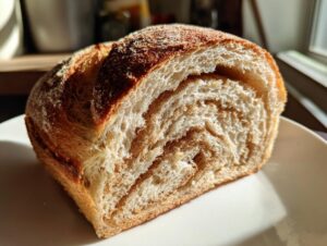 Close-up of a slice of pumpkin sourdough bread showing a beautiful cinnamon swirl pattern inside.