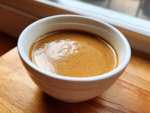 Close-up of rich, smooth turkey gravy with a slight froth in a small white bowl.