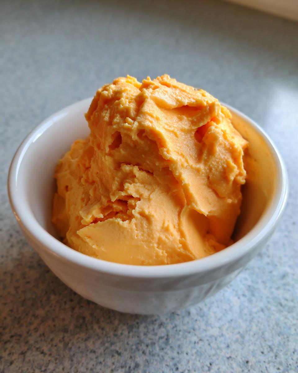 A scoop of bright orange, thick beer cheese dip served in a small white bowl.