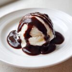 A scoop of vanilla ice cream generously drizzled with silky chocolate sauce recipe.