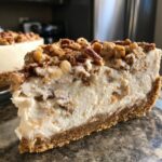 Close-up of a thick slice of pecan cream pie showing a graham cracker crust, creamy filling, and pecan topping.