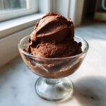 A perfect scoop of rich, dark chocolate mousse served in a clear glass dish.