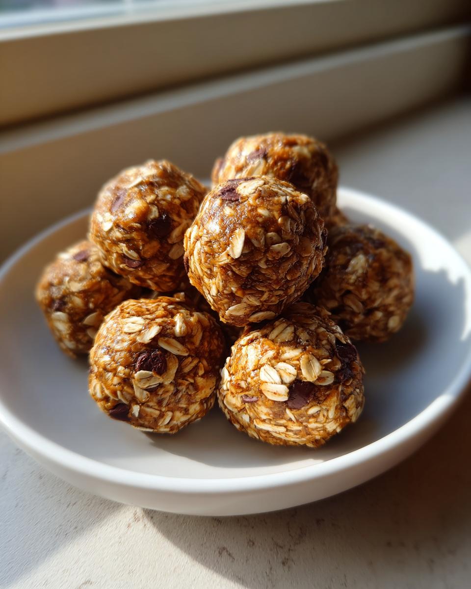A stack of homemade protein balls made with visible oats and chocolate chips, sitting on a white plate.
