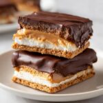 Two stacked bars of buckeye graham crackers featuring layers of graham, marshmallow, peanut butter, and chocolate coating.