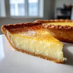 Close-up of a thick slice of creamy buttermilk pie showing the golden-brown top and flaky crust.