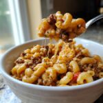 A spoonful of cheesy homemade hamburger helper, showing melted cheese stretching from the bowl.