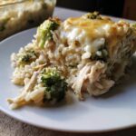 Close-up of a serving of creamy chicken broccoli rice casserole topped with melted, slightly browned cheese.