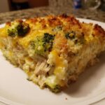 A close-up slice of creamy Chicken Divan featuring shredded chicken, broccoli florets, and a crispy, cheesy topping.