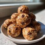 A close-up stack of homemade chocolate chip protein balls made with visible rolled oats.