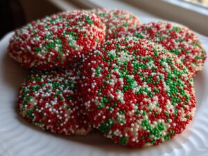 A stack of round christmas sprinkle cookies completely covered in red, green, and white nonpareils.