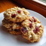 A stack of three delicious cranberry oatmeal cookies featuring white chocolate chips and dried cranberries.