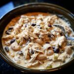 Close-up of a hearty bowl of creamy white cream cheese chicken chili loaded with shredded chicken, white beans, and black beans.