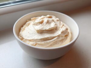 A white bowl filled with thick, creamy, pale yellow 3-ingredient fruit dip, set on a white countertop.