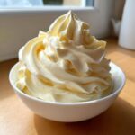 A perfect swirl of creamy, pale yellow banana ice cream served in a small white bowl.