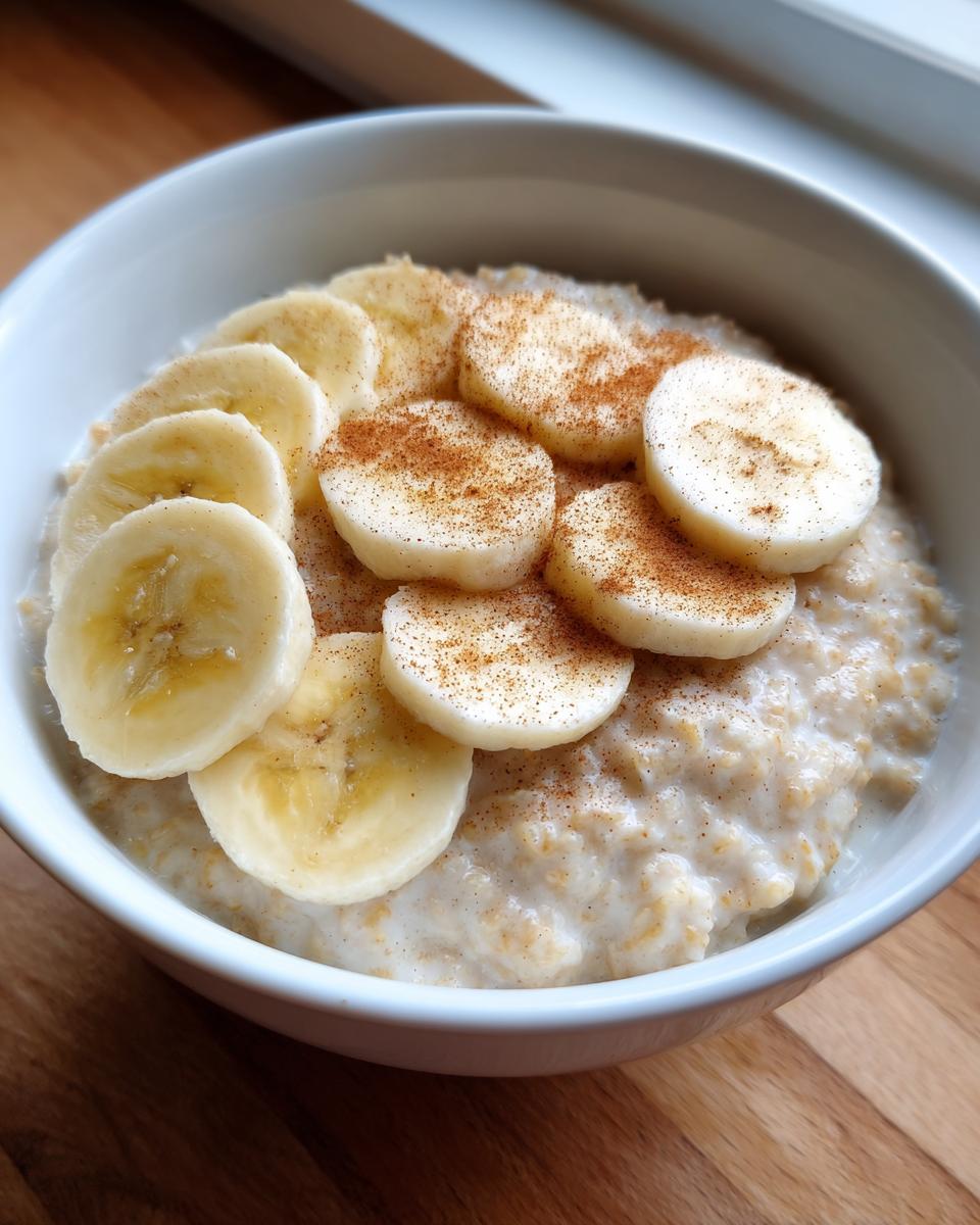 Close-up of creamy banana oatmeal topped with sliced bananas and a dusting of cinnamon.