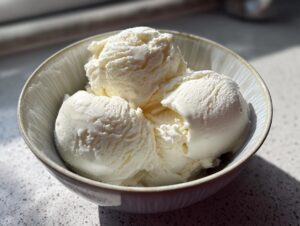 Three scoops of creamy white cottage cheese ice cream served in a light-colored bowl.