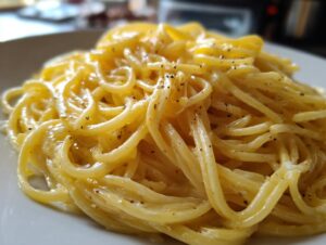 A close-up shot of perfectly coated spaghetti noodles in a rich, creamy lemon pasta sauce, seasoned with fresh black pepper.