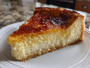 A close-up of a slice of creme brulee cheesecake showing the creamy filling and caramelized sugar topping.