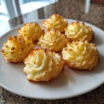 Seven golden-brown, piped Duchess potatoes arranged on a white plate, showing crispy edges.