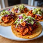 Four delicious salmon tacos topped with vibrant purple and green slaw on a white plate.