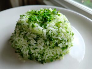 A perfectly molded serving of fluffy cilantro lime rice, topped with fresh chopped herbs, on a white plate.