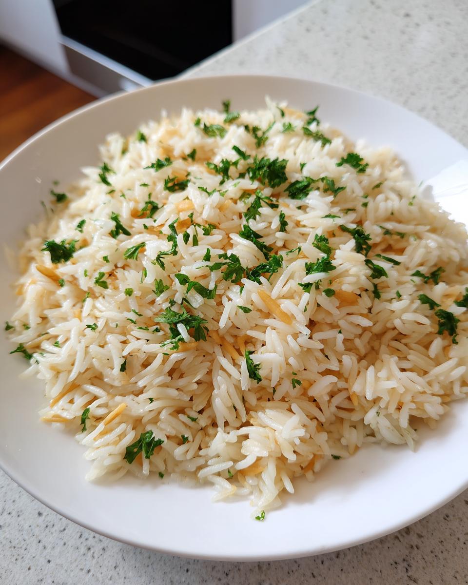 A close-up of fluffy rice pilaf mixed with toasted vermicelli and topped with chopped fresh parsley.