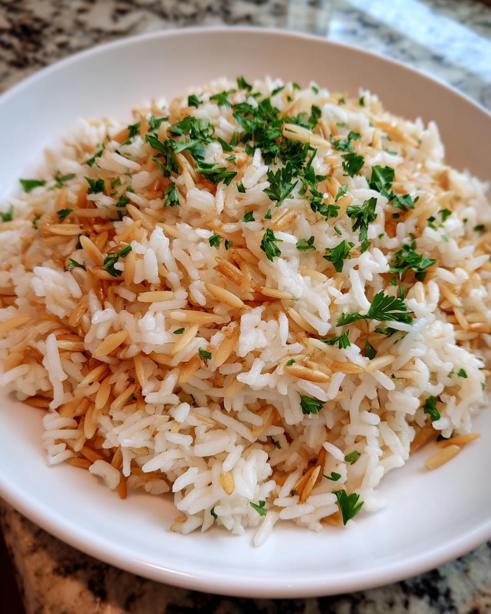 Close-up of fluffy rice pilaf mixed with toasted vermicelli and topped with fresh chopped parsley.