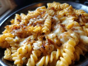 A close-up shot of creamy french onion pasta featuring fusilli noodles, melted cheese, and caramelized onions.