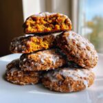 A stack of soft, spiced persimmon cookies drizzled with white glaze, one cookie broken open to show the moist center.