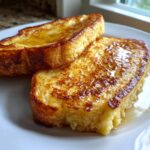 Two golden brown slices of easy french toast drizzled with syrup on a white plate.